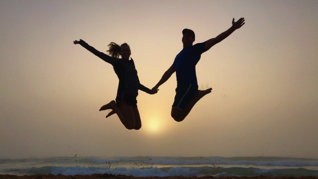 Jordan and Vanessa leaping together on the beach at sunset